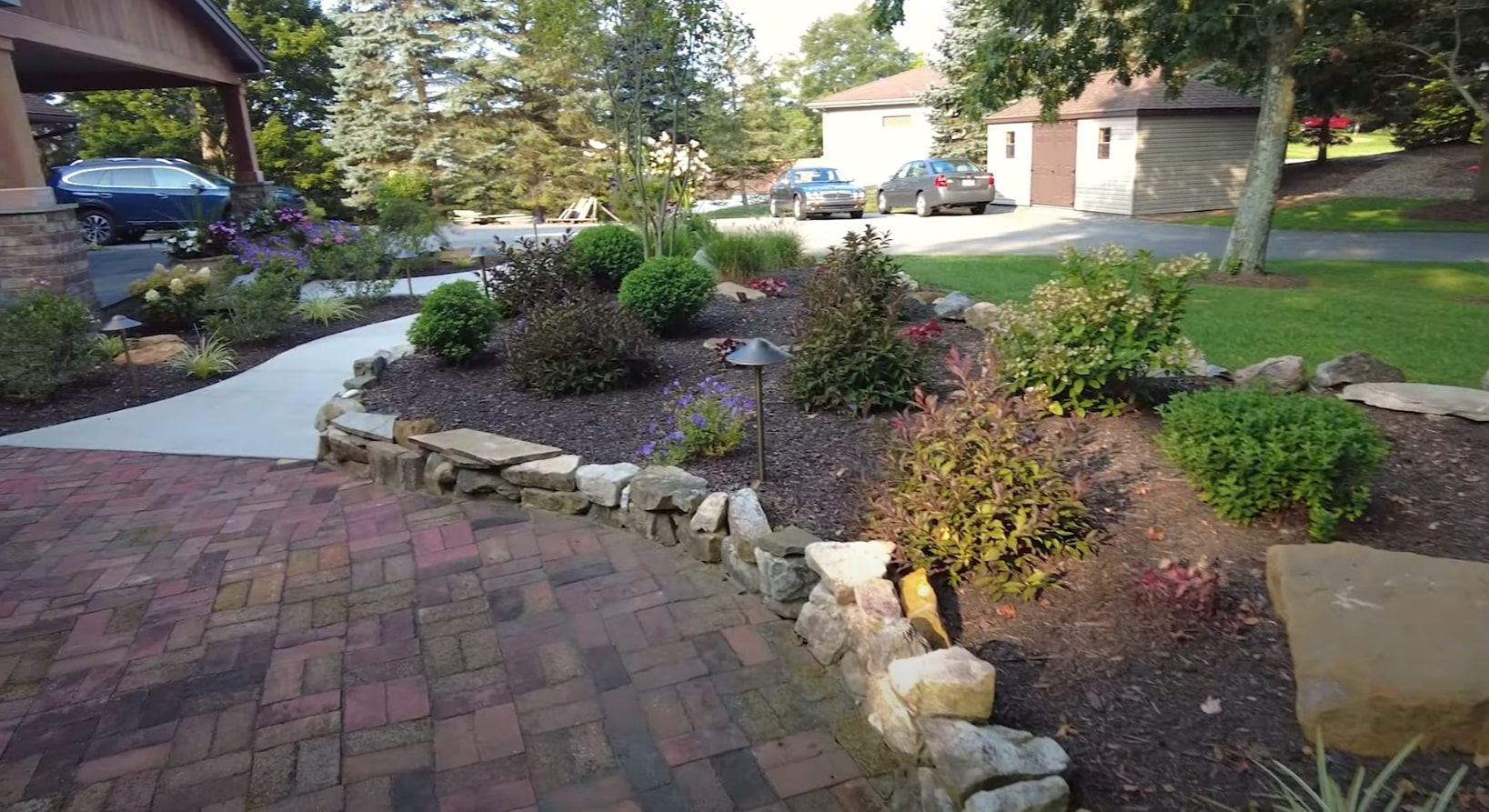 Custom front yard landscaping with stone retaining walls and drought-resistant plantings Front yard landscape design with natural stone retaining walls and colorful plantings
